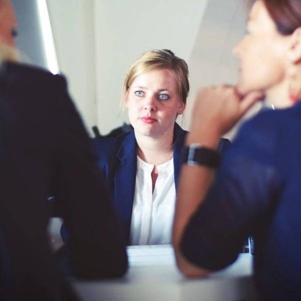 Drei Personen besprechen Unterlagen an einem Tisch.