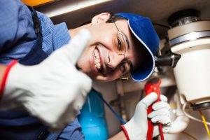 Handwerker mit Werkzeug arbeitet an Leitungen unter einer Küchenspüle