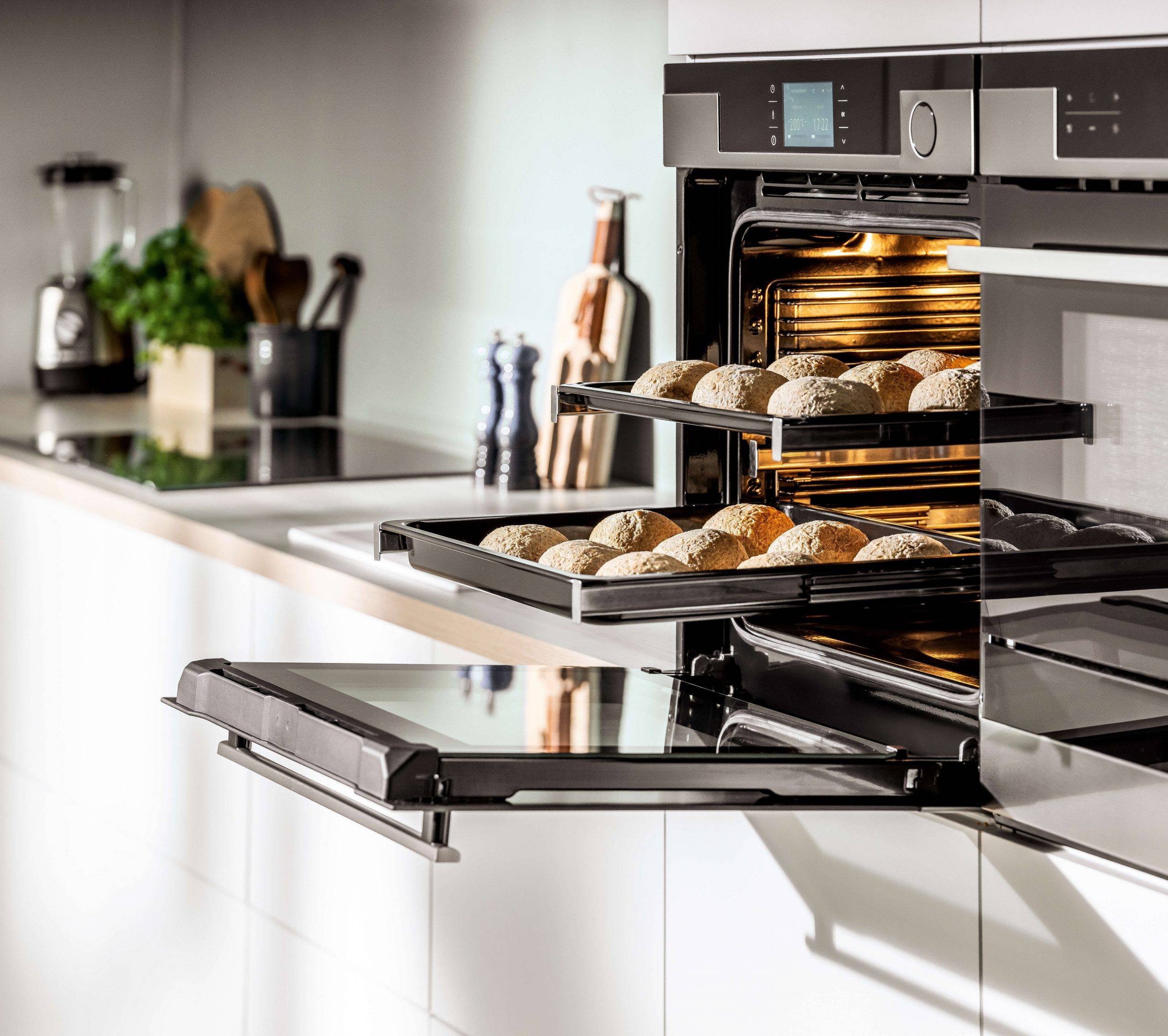Geöffneter Backofen mit ausgezogenen Backblechen in einer Küchenhochschrankwand