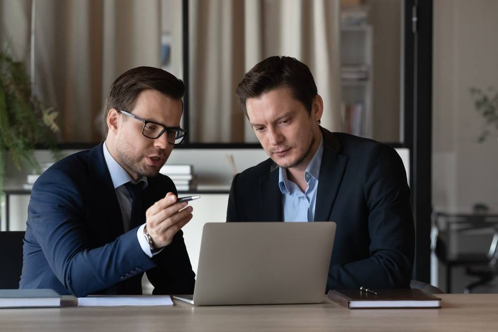 Gutachter und Anwalt – abgestimmte Aufgaben Zwei Männer besprechen Unterlagen an einem Laptop.