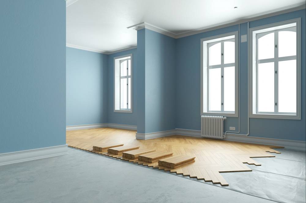 Teilweise verlegter Holzfußboden in einem Raum mit blauen Wänden